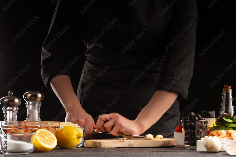 Chef cooks by chopping garlic. Against the background of vegetables. Cooking, tasty and wholesome food. Chef cooks by chopping garlic. Against the background of vegetables. Cooking, tasty and wholesome food.