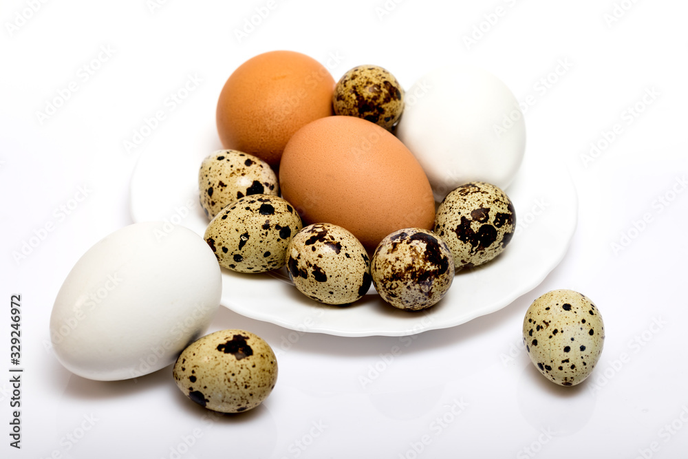 Obraz premium Chicken and quail eggs on a plate on a white background.