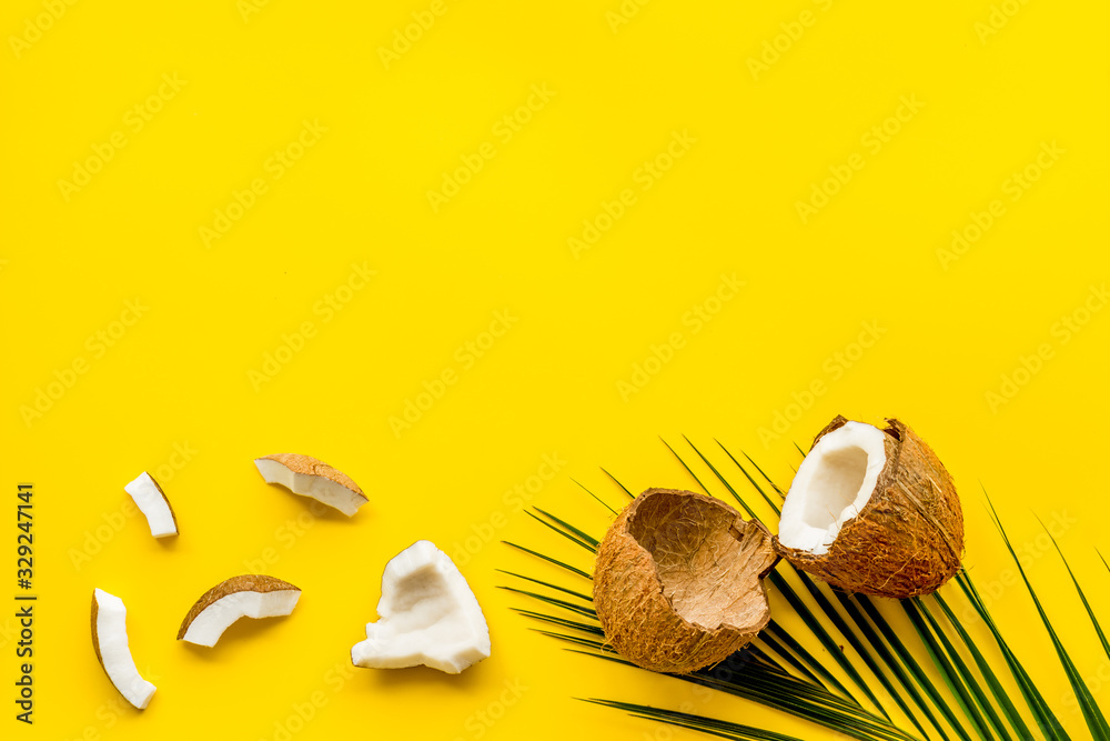 Coconuts frame. Nuts pieces and exotic leaves on yellow background top-down copy space Coconuts frame. Nuts pieces and exotic leaves on yellow background top-down copy space