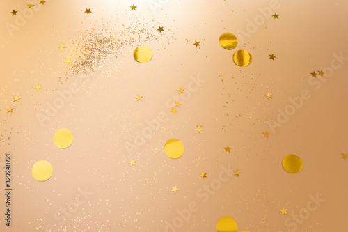 Gold confetti and glitter on beige metallic shiny background
