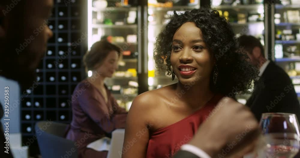 Close up of joyful African American couple laughing while sitting at table in restaurant. Attractive man and woman in love talking and joking at dinner. First date of young male and female clients. Close up of joyful African American couple laughing while sitting at table in restaurant. Attractive man and woman in love talking and joking at dinner. First date of young male and female clients.