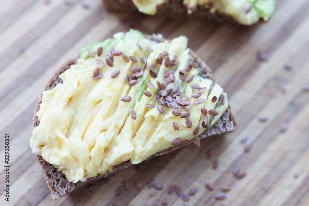 whole grain toast with avocado and flax seeds on a wooden board whole grain toast with avocado and flax seeds on a wooden board