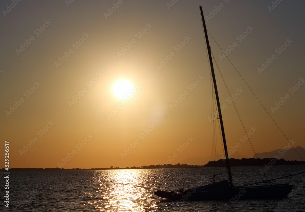sailboat moored on the sea at sunset and headland on the background
