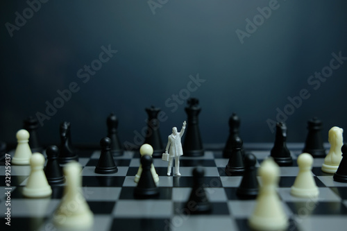 Business strategy conceptual photo - Miniature businessman pointing up in the middle of a chess piece that falls on the chessboard