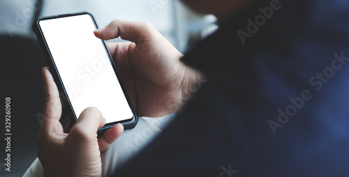 Cropped shot view of man hands holding smart phone with blank copy space screen for your text message or information content, female reading text message on cell telephone during in urban setting. 