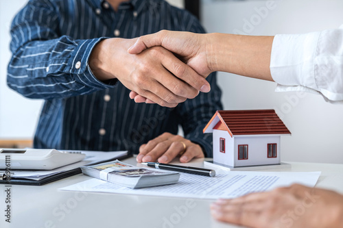 Real estate agent and customers shaking hands together celebrating finished contract after signing about home insurance and investment loan, handshake and successful deal