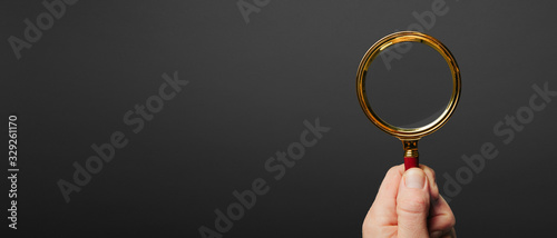 man holds a magnifier on a black background