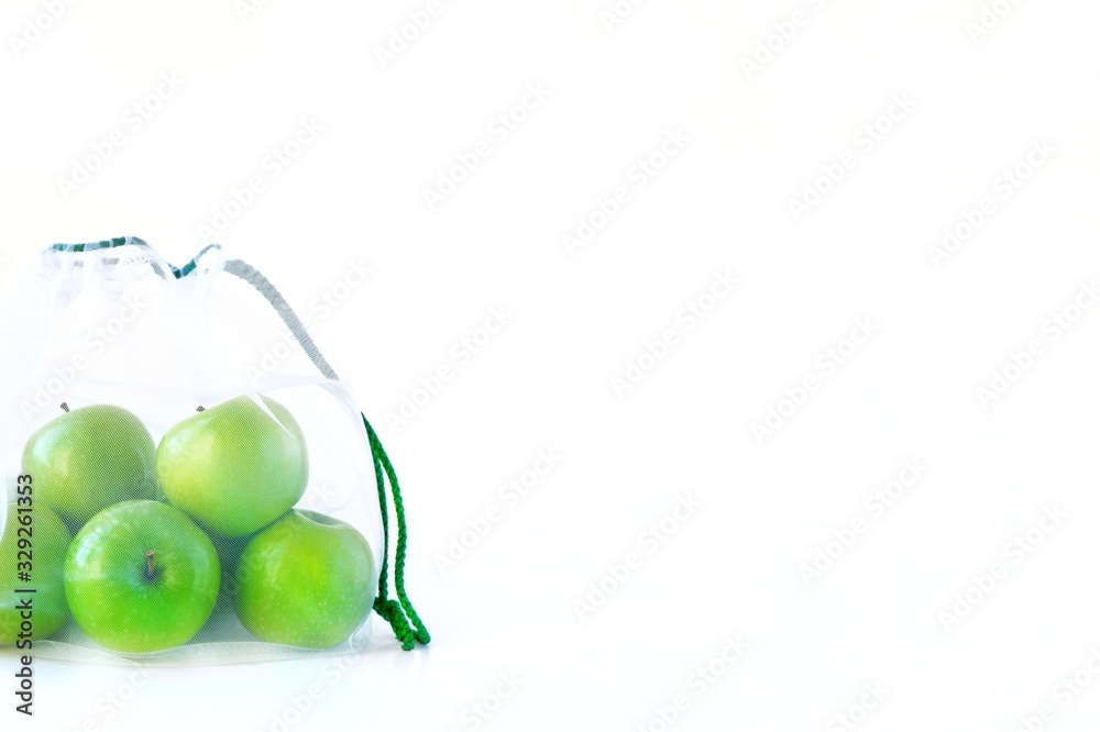 Reusable eco friendly mesh bag with green apples on a white background. Sustainable lifestyle concept, Zero waste shopping, Ecological.Copy space for text. Reusable eco friendly mesh bag with green apples on a white background. Sustainable lifestyle concept, Zero waste shopping, Ecological.Copy space for text.