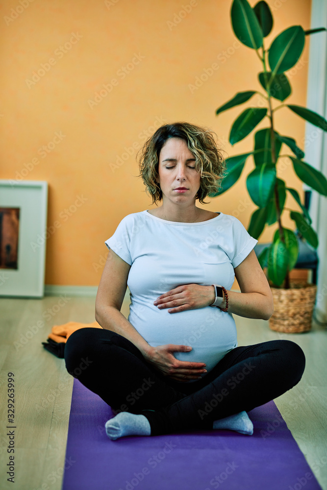Mid-adult fit pregnan Caucasian woman practicing yoga. Morning time.	
