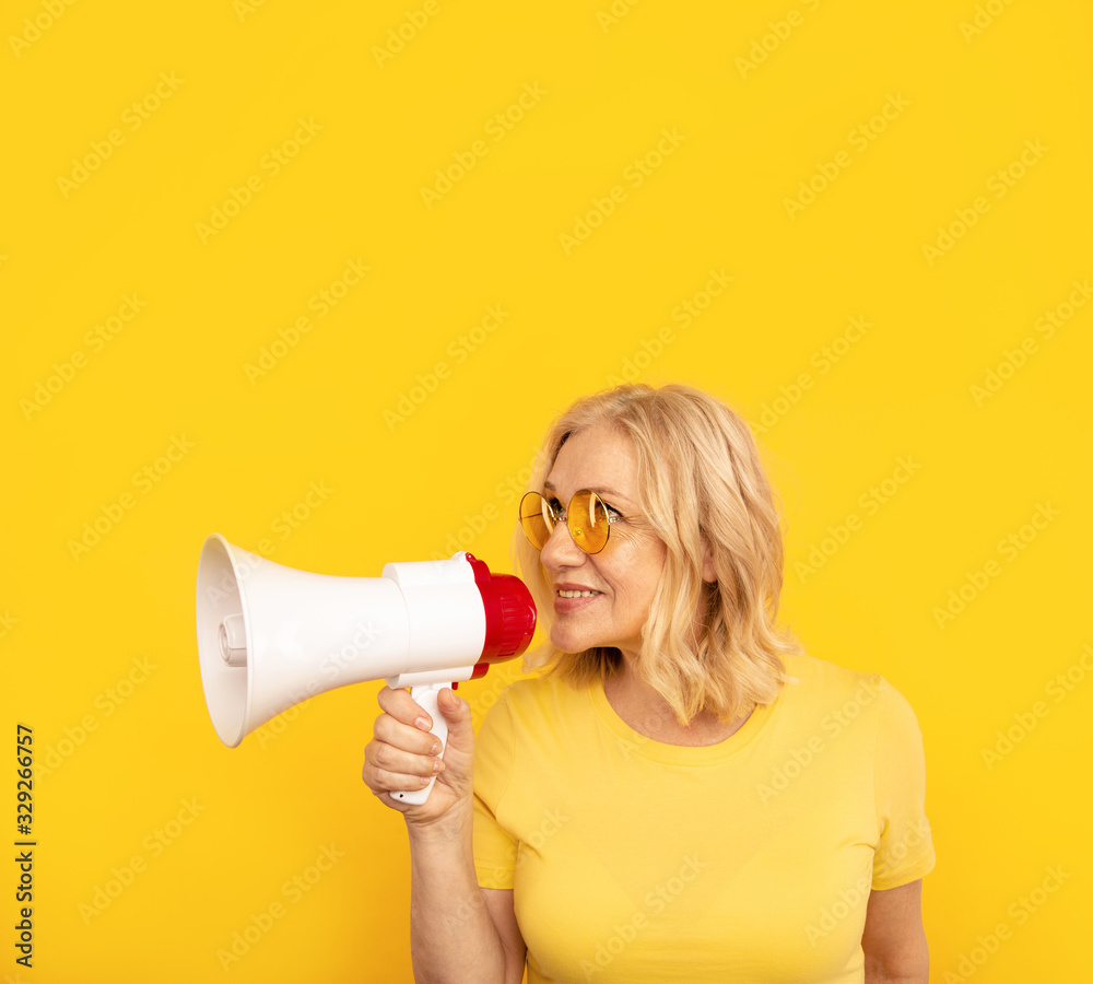 Naklejka premium Woman with megaphone isolated in the yellow studio