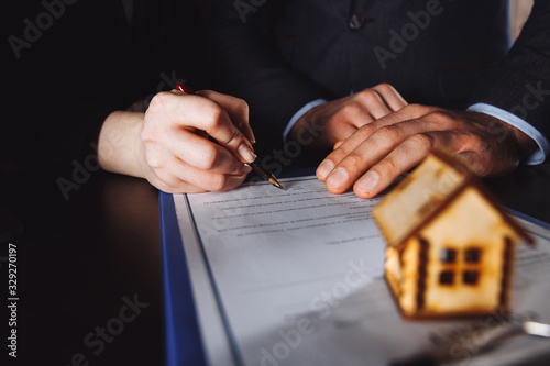 Key of home on hand of bank employeer to sell house after approve loan and buyer signing in contract paper in office photo