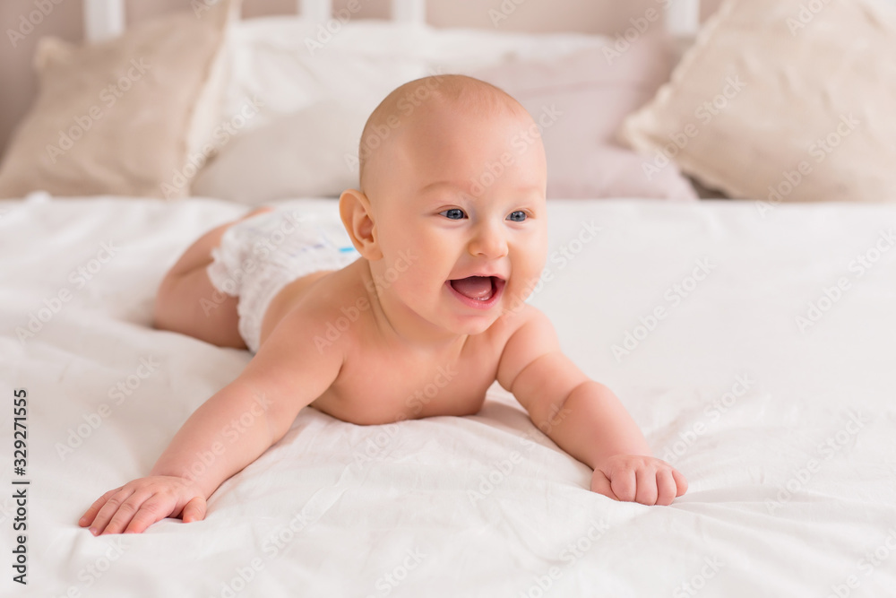 baby boy smiling and lying on a light bed at home baby boy smiling and lying on a light bed at home