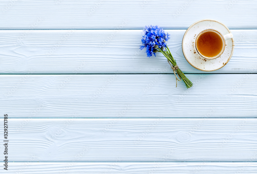 Summer tea party. Cup near cornflowers bouquet on blue wooden background top-down copy space Summer tea party. Cup near cornflowers bouquet on blue wooden background top-down copy space