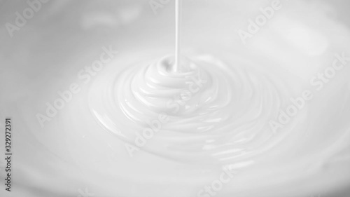 Slow motion of white cream or body lotion drop on skin care background with abstract wave.