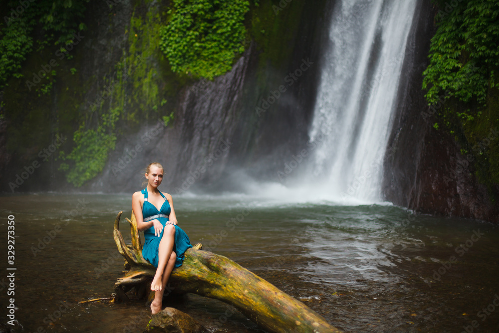 beautiful girl walks near a waterfall