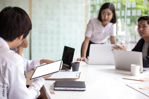 A team of Asian business owners are teaching job for new people using computers. New employees are being trained by business owners.