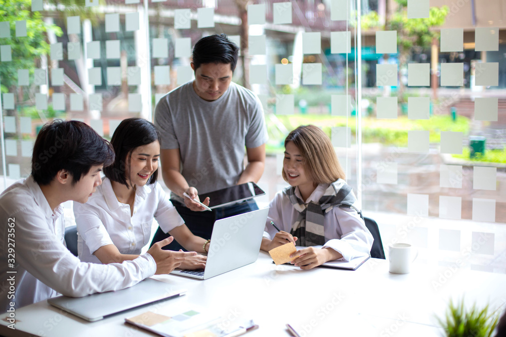 A team of Asian business owners are teaching job for new people using computers. New employees are being trained by business owners.