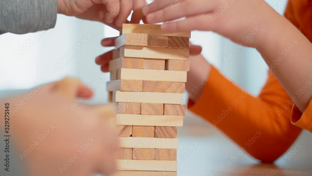 Young girls build a tower of wooden sticks. Board game.