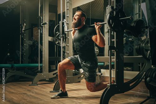 Fit man doing squats in a training machine