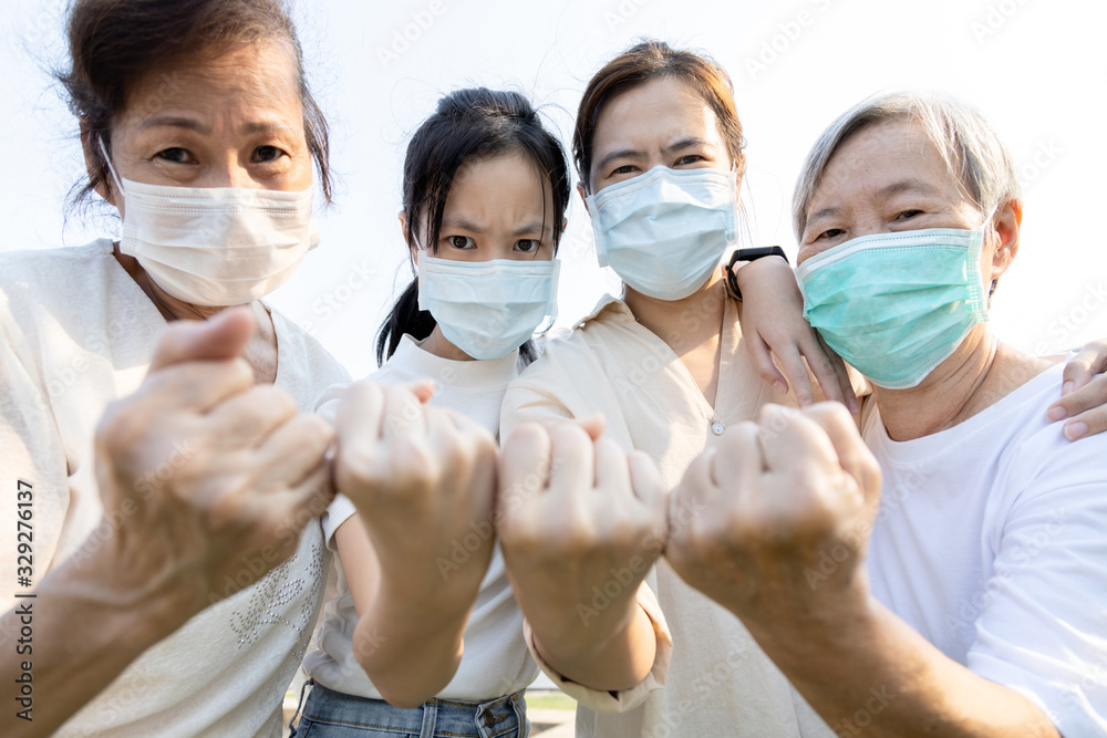 Group of people with medical mask to prevent infection from spreading of Covid-19,asian family raised a fists and prepare for the epidemic,fight the Coronavirus,overcoming a terrible crisis together