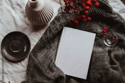 Winter autumn mock up with white book cover. Greetings card new year book mockup with red rowan berries over gray wool plaid. White book cover winter cozy mock-up.Warm festive rowan tree backdrop. photo