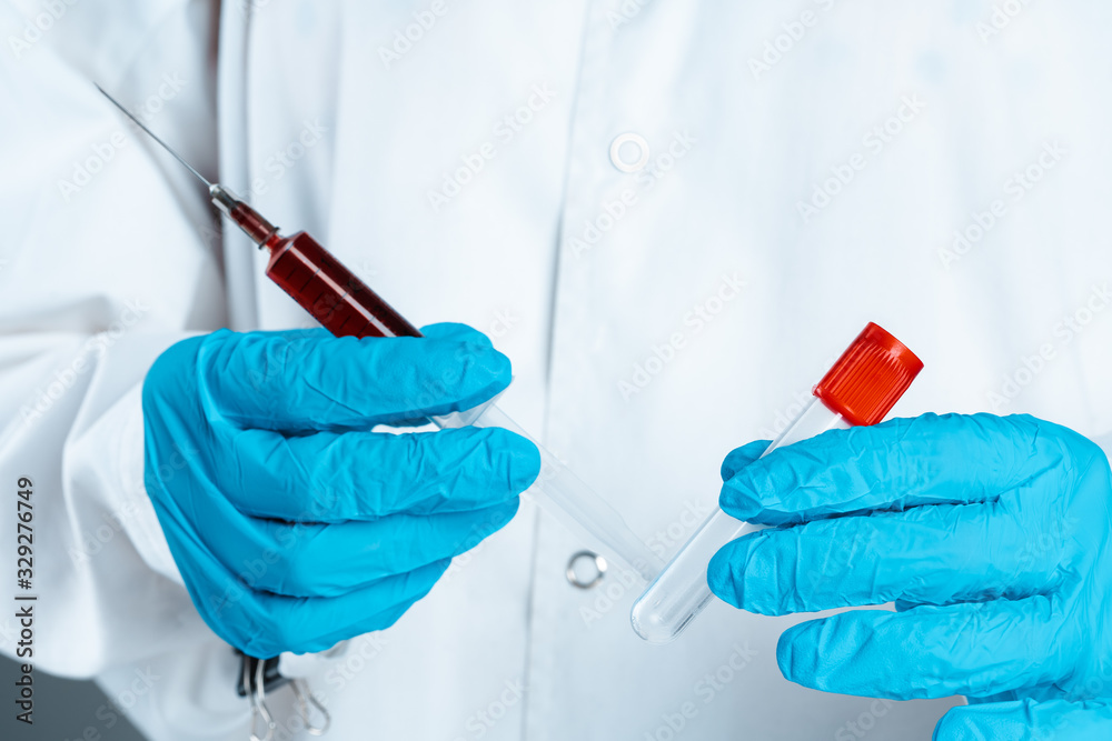 Doctor in blue gloves keep in hands test tube with a blood and syringe Doctor in blue gloves keep in hands test tube with a blood and syringe