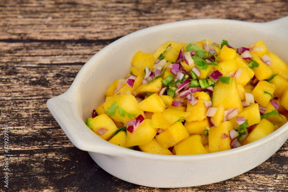 Fresh homemade mango salsa in a bowl on wooden background