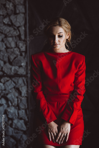 Beautiful sad woman lady in a red dress in a room in the loft style. Soft selective focus. Beauty, fashion.