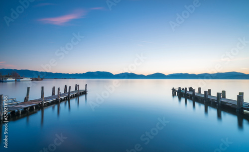 Two Wooden pier or jetty at sunset and sky reflection on water. Versilia Tuscany, Italy
