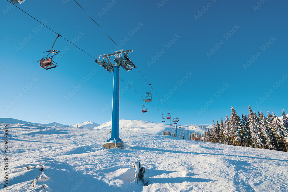 Ski lift with seats going over the mountain and paths from skies and snowboards. Beautiful winter landscape. Ski lift with seats going over the mountain and paths from skies and snowboards. Beautiful winter landscape.