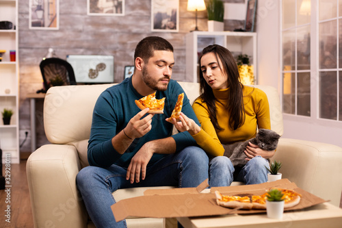 Gorgeous young couple eating pizza while watching TV