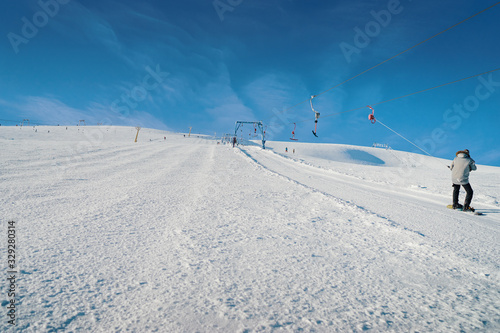 Ski lift going over the snowy mountain and paths from skies and snowboards.