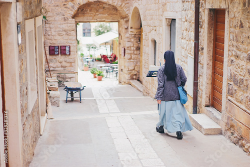 Back view of catholic nun walking down ancient europian street. © luengo_ua