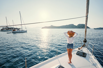 Luxury travel on the yacht. Young happy woman on boat deck sailing the sea. Yachting in Greece.