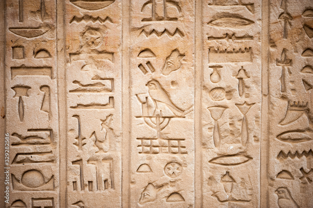 Full frame close-up of series of Egyptian hieroglyphs carved into rough stone temple wall in Luxor, Egypt