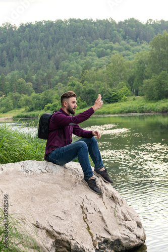 young man using cellphone, bearded hipster traveler doing selfie. Vacation, tourism, internet, technology concept