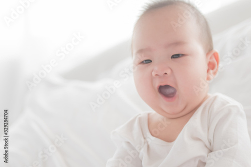 newborn child relaxing in bed. adorable baby boy in white sunny bedroom. nursery for young children. textile and bedding for kids. family morning at home. six month. childhood and baby care concept.