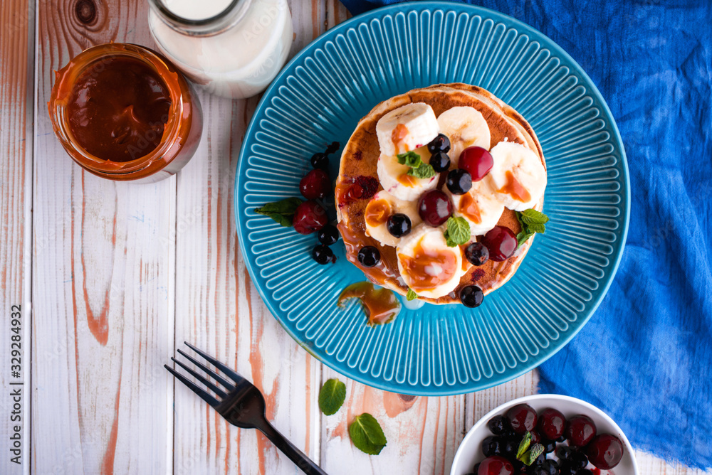 Delicious and lush pancakes with fresh fruits and berries, poured with salted caramel.
