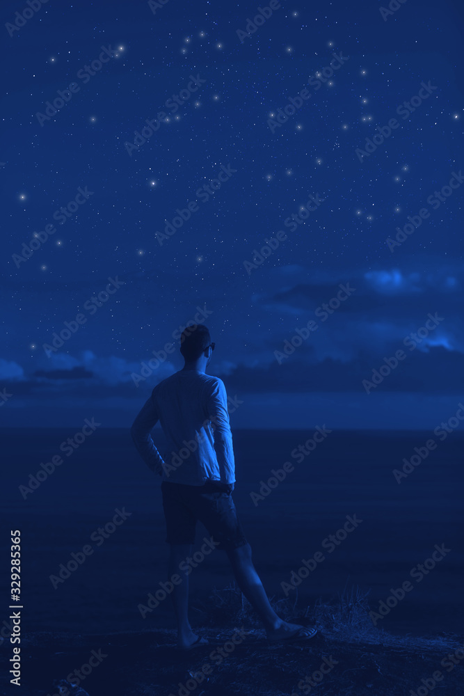 Fototapeta premium Silhouette of a man with milky way stars above the ocean horizon.