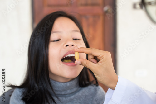 cute little girl having sick and happy to taking medicine in mouth. .Kid having pharmaceutical medical dose for pain relief or antibiotic medication curing from illness. healthcare medicine concept .