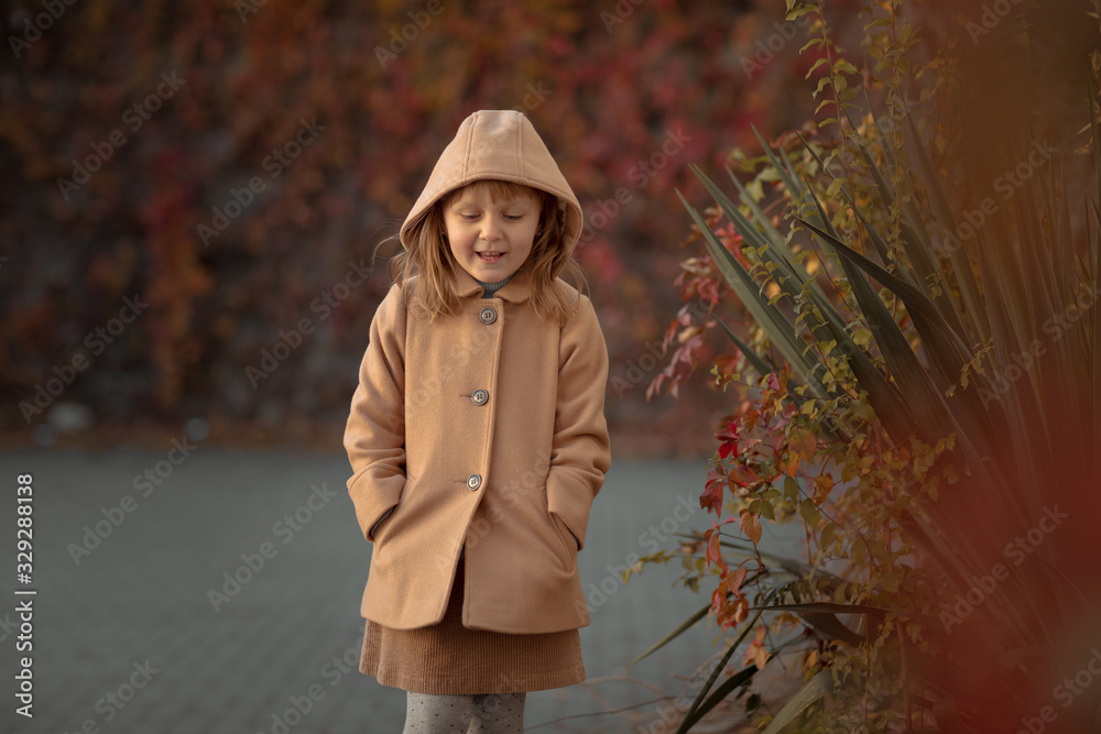 Girl child aged 6 years dressed in autumn coat on a walk.