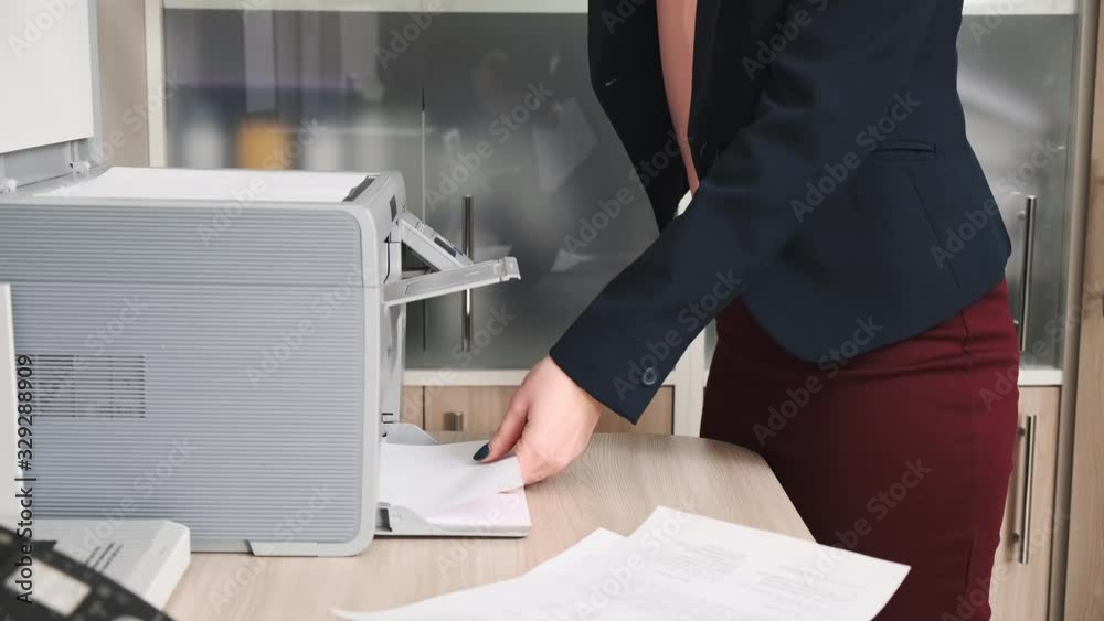 A young woman in a jacket, an office worker prints documents on a copy machine. Paperwork. A young woman in a jacket, an office worker prints documents on a copy machine. Paperwork.