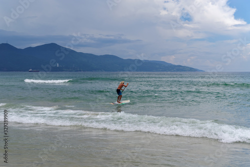 Stand up paddling on the seashore against mountain and sky