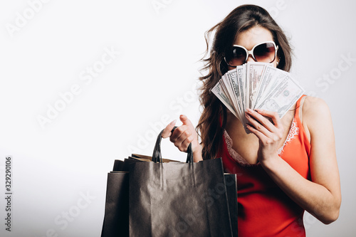 Foto Chic brunette woman in red dress and sunglasses covering her face with a bunch o