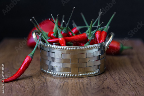 Red hot chili peppers in vintage metal bowl on wooden table. Food background
