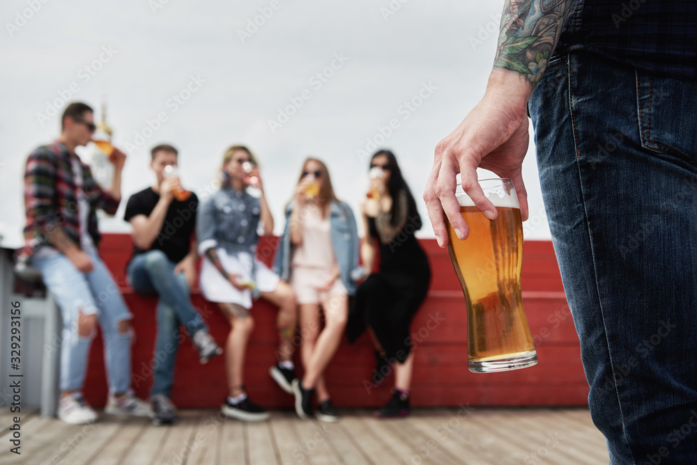 © mirage_studio - Close up of light beer in male hand with group of friends on background in blur, copy space. Friendship and celebration concept © mirage_studio - Close up of light beer in male hand with group of friends on background in blur, copy space. Friendship and celebration concept