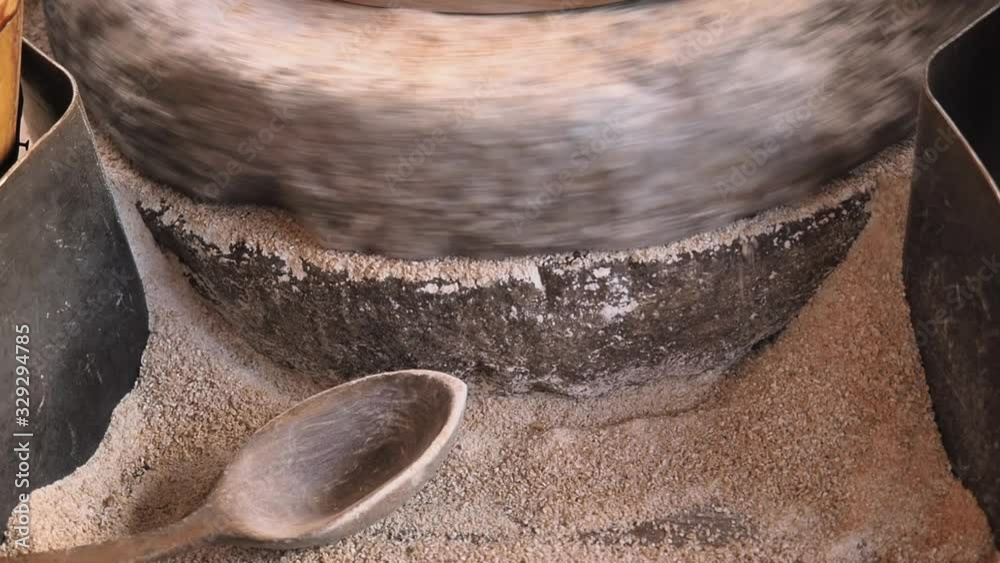Closeup footage a process of grinding grain on an old millstone of
