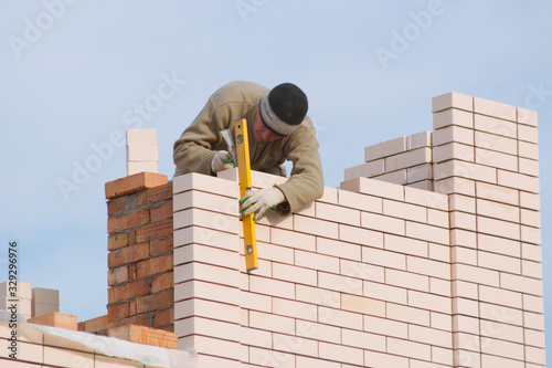 A bricklayer puts a facing brick. A bricklayer works on building a house - he puts a white facing brick