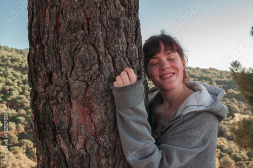 Close-up of a woman hugging a tree in the field