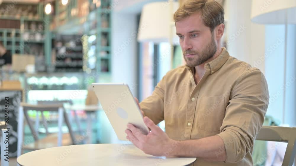 Attractive Young Man with Digital Tablet in Cafe Attractive Young Man with Digital Tablet in Cafe